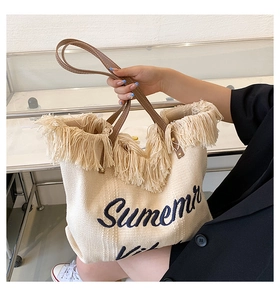 Détail du sac fourre-tout en toile blanc cassé avec franges et broderie Summer bleue