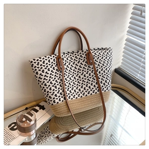 Detail of woven tote bag with monochrome pattern and brown leather straps in natural light