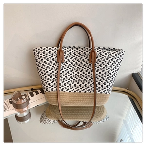 Detail of woven tote bag with black and white texture and brown leather straps
