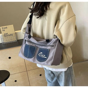 Detail view of the gray fabric crossbody bag with blue denim pockets and adjustable strap