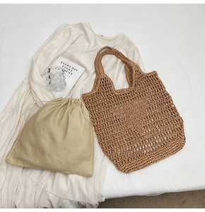 Close-up of woven straw tote bag and drawstring inner pouch on white textured dress