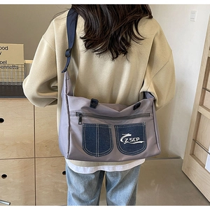 Detail of grey-purple crossbody bag featuring denim pockets and adjustable blue strap