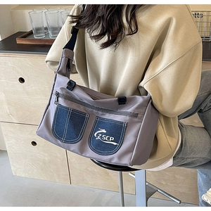 Detail view of neutral gray nylon crossbody bag with blue denim pockets and ZSCP logo
