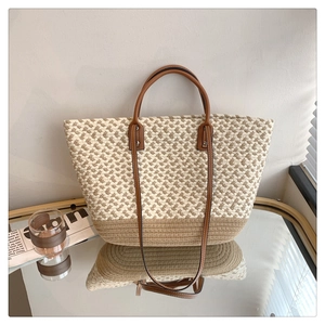 Detail view of woven tote bag texture with brown leather handles and sturdy metal rivets