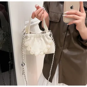 Detail of cream pleated cloud bag with pearl chain handle and metallic strap