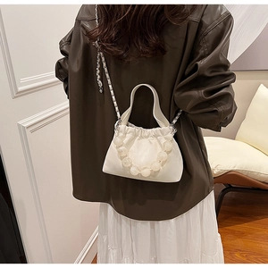 Detail of off-white pleated cloud bag with large beaded handle and silver chain strap