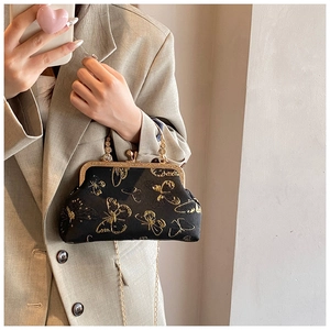 Détail du sac en soie noire avec broderie papillon dorée et bandoulière en chaîne chic
