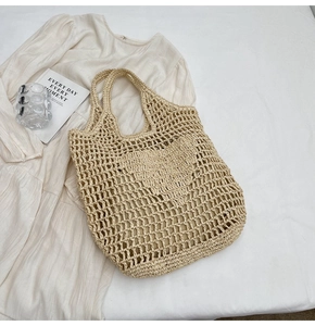 Detail of hand-woven straw tote bag with heart-shaped cutout and cotton lining