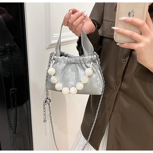 Detail of silver metallic bucket bag with faux pearl handle and pleated closure