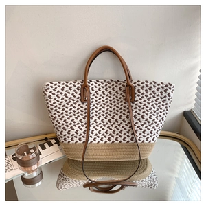 Detail of woven tote bag with herringbone pattern and brown leather straps on mirror surface
