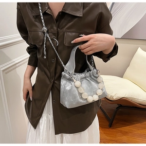 Detail view of silver pleated PU handbag featuring a pearl handle and silver chain strap