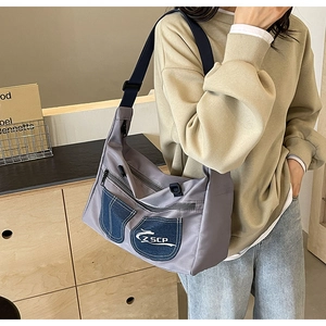 Gray large tote bag with blue denim pockets and adjustable black shoulder strap