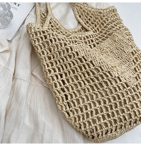 Detail of hand-woven beige straw bag featuring intricate honeycomb texture on linen