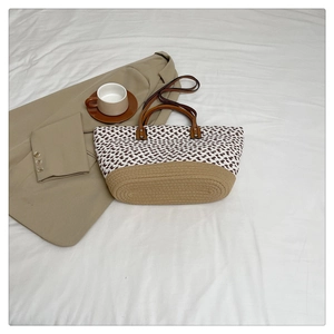 Detailed top view of a handmade woven tote bag with brown leather handles on white fabric