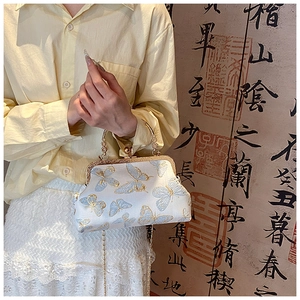Détail du sac bandoulière en soie avec broderie papillon bleu et poignée perle