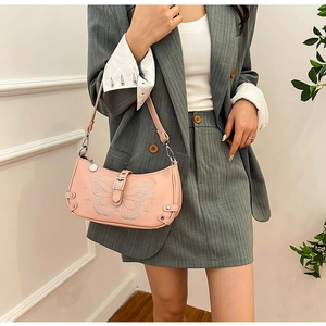 Dettaglio della borsa hobo rosa con ricamo a farfalla d'argento indossata dal modello