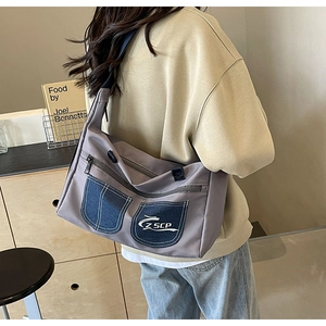 Close-up of gray fabric crossbody bag with blue denim pockets and adjustable strap