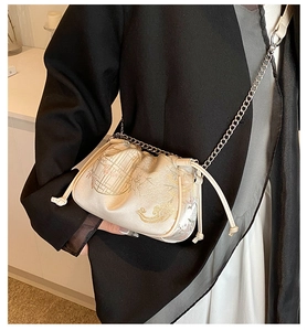 Detail of silk texture crossbody bag featuring traditional embroidery and chain strap