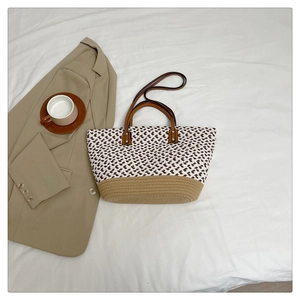 Detail of woven tote bag with geometric patterns, khaki base, and leather straps