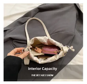 Detail view showing the spacious interior of the champagne satin floral bucket bag