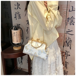 Détail du sac en jacquard de soie blanc avec motifs papillons et fermoir doré en métal