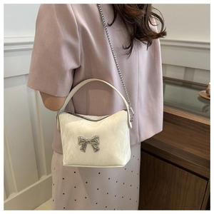 Gros plan du sac bandoulière en similicuir blanc cassé avec nœud métallique et chaîne argent