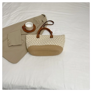 Detail of bohemian woven bag featuring two-tone heart pattern and faux leather handles