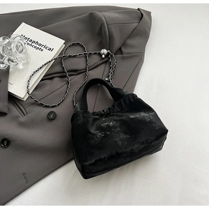 Minimalist black velvet handbag with silver chain and sphere detail shown on grey blazer