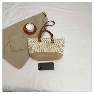 Detail of bohemian straw tote bag with color-block weave design and shoulder straps