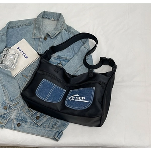 Minimalist black nylon crossbody bag with denim pockets and adjustable strap on white fabric