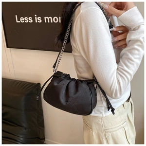Detail of black cloud bag featuring dark floral textured fabric and metal chain strap