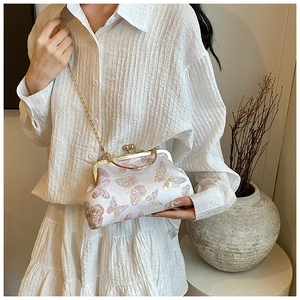 Sac à main crème chic avec motif papillon violet et chaîne dorée présenté par un modèle
