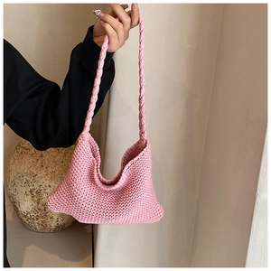 Close-up of pink knit handbag featuring thick yarn weave and textured braid handle details