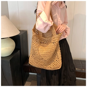 Detail of hand-woven straw shoulder bag showing large hollow-out mesh pattern in natural tan