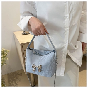 Détail du sac à main en PU bleu clair avec nœud en métal argenté et tissu texturé