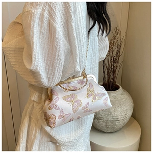 Détail du sac bandoulière en soie blanche avec broderie papillon et poignée dorée
