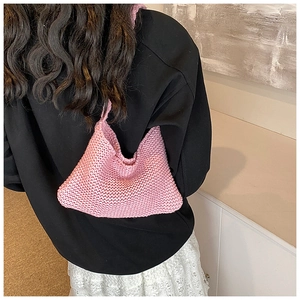 Detail of pink knitted handbag featuring textured crochet pattern and minimalist top handle