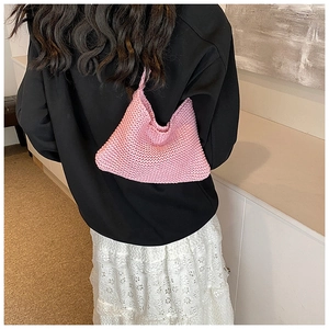 Close-up of pink hand-woven knit tote bag showing intricate texture on a female model