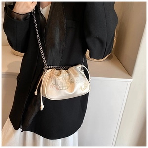 Detail of champagne satin crossbody bag with floral embroidery and chain strap