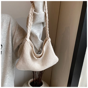 Detailed texture of off-white hand-knitted tote bag with chunky braided shoulder strap