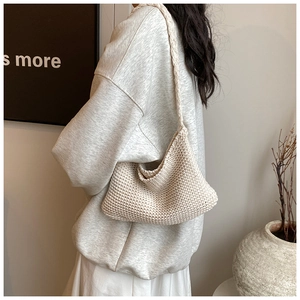 Close-up of cream knitted shoulder bag showing thick cotton weave texture and strap