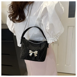 Détail du sac bandoulière en PU plissé noir avec un nœud argenté et bandoulière chaîne