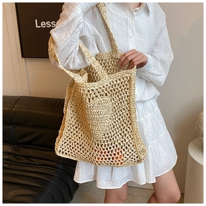 Detail view of woven straw shoulder bag with hollow mesh design and inner pouch