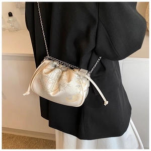 Detailed macro view of cream silk satchel with bamboo jacquard pattern and silver chain