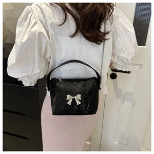 Détail du sac bandoulière noir en PU plissé avec un nœud métallique argenté et une chaîne