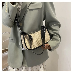 Détail du sac croissant tissé avec bordure en cuir noir et rivets métalliques argentés