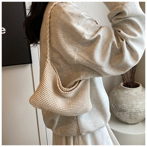 Detailed knit texture of a beige crochet shoulder bag shown in a lifestyle setting