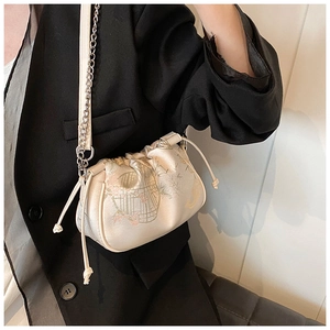Detail of silk satin crossbody bag featuring elegant floral bird embroidery and chain