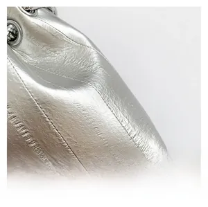 Close-up of metallic silver PU leather texture with fine stitching and pleat details