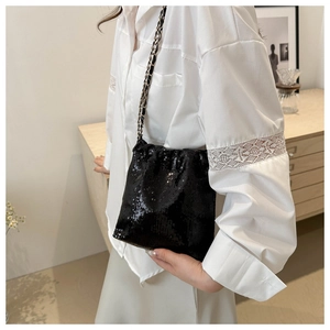 Detail of black sequin crossbody bag with metallic chain strap and drawstring design